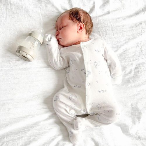 Baby der sover ved siden af sin MAM sutteflaske